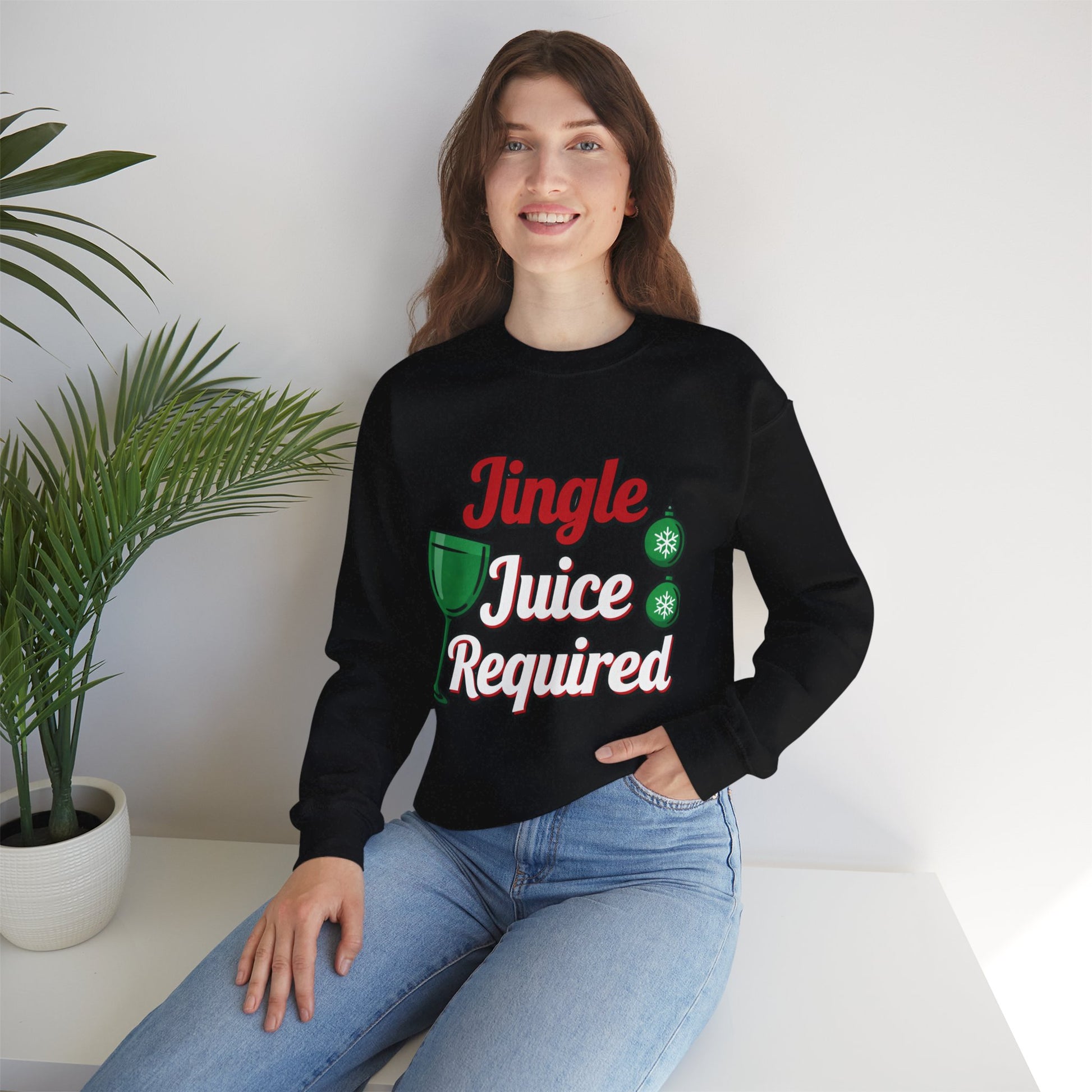 Person wearing a black sweatshirt with 'Jingle Juice Required' text, sitting on a white surface with a plant in the background.