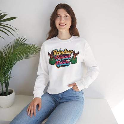 Person wearing a white sweatshirt with 'Reindeer Squad Goals' design sitting on a white surface.